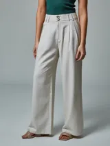 Pantalón de vestir color crudo, de corte recto, con bolsillos laterales y traseros. Se ajusta a la cintura con cinturón de cuero marrón.