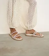 Sandalia plana mule color crema con punta redonda y tiras finas con brillos.