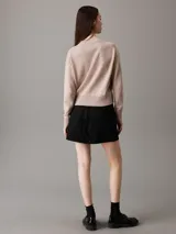 Sweater color beige de punto de algodón orgánico, con cuello redondo alto, mangas largas y logo bordado en el pecho.