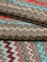 Bufanda tipo chalina de tejido de punto con diseño de ondas en zigzag multicolor y flecos en los extremos.