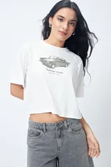 Remera cropped blanca de mangas ranglan con estampa frontal de un auto antiguo y texto "Vintage Gems / retro car club".