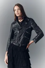 Campera de cuero ovino negra, estilo rocker, con cuello con solapas, cierre cruzado, cinturón ajustable en la cintura, charreteras en los hombros y múltiples cierres metálicos decorativos. Forro de poliéster.