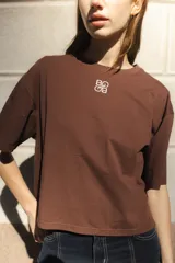 Remera negra de algodón con corte cuadrado, cuello redondo y logo bordado en color naranja.