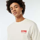 Remera color crema con estampado rojo en la espalda que dice 'Los Angeles Sunset Hours California Golden State'.