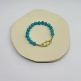 Pulsera con cuentas de ágata celeste de 8 mm de diámetro, separadores de hilo turquesa y cierre de acero hipoalergénico con baño de oro.