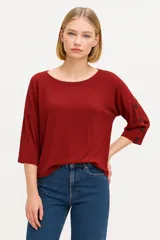 Remera color ladrillo de viscosa y elastano, con cuello redondo, mangas 3/4 con botones y corte holgado.