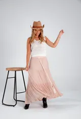 Pollera larga color rosa pálido, de voile de algodón y viscosa, con tres volados y cordón ajustable en la cintura.