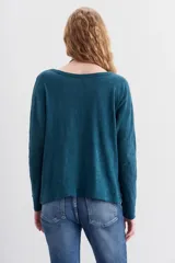 Remera blanca de algodón con calce relajado y cuello redondo. Tiene mangas largas que se ajustan hacia los puños.