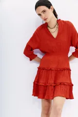 Vestido corto de viscosa color rojo con efecto crinkle, escote redondo, mangas largas con volados y cintura elastizada.