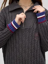 Sweater tejido de algodón color rosa claro, con cuello polo con cierre de cremallera metálica y mangas largas con puños a rayas de colores.