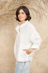 Camisa blanca de lino con cuello mao, mangas 3/4 con botón para sujetar, cierre con botones a tono y ajuste con cordón en la cintura.