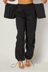 Pantalón cargo negro con cintura elástica, corte holgado, bolsillos laterales y detalle de falda superpuesta en la parte delantera.