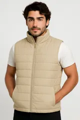Chaleco acolchado color beige con cierre frontal y bolsillos laterales.