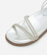 Sandalia plana plateada con tiras finas adornadas con strass y cierre de hebilla en el tobillo.