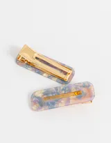 Set de dos hebillas rectangulares para el pelo con diseño abstracto en tonos lila, beige y azul.