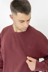 Buzo color bordó con cuello redondo y mangas largas. Estampado en la espalda con la palabra 'Pulau' en relieve.