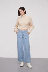 Sweater corto color crema, de tejido de punto trenzado, con cuello alto y mangas largas abullonadas.