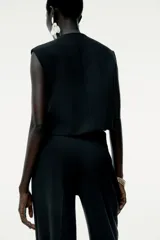 Top tipo chaleco negro de Zara Woman Collection, con cuello redondo y sisa. Presenta costuras a contraste y cierre frontal con botones.