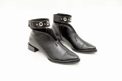 Botín de cuero color borgoña con taco bajo, corte en V en el empeine, pulsera con detalles metálicos y cierre lateral.