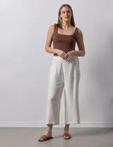 Pantalón de lino color crudo, de corte ancho y tiro alto, con bolsillos laterales y cintura elástica.