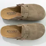 Zuecos de cuero gamuzado color beige, con plantilla anatómica de corcho, suela de goma negra y hebilla lateral ajustable.