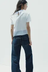 Camiseta blanca de cuello redondo con solapa combinada a contraste de rayas celestes. Manga corta. Bajo con tejido combinado de rayas celestes. Cierre en espalda con abertura y botón.