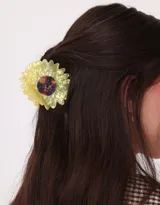 Broche para el pelo con forma de margarita amarilla y centro marrón.