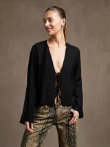 Blusa negra con estampado animal print en blanco y marrón, escote en V con lazo ajustable y mangas largas acampanadas.