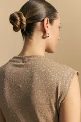 Top sin mangas negro, con cuello alto y hombros ligeramente estructurados. El tejido presenta una textura sutil con brillo integrado que simula un animal print.