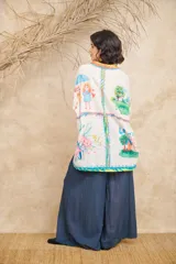 Camisa de manga corta con cuello clásico y cierre frontal con botones. Presenta un estampado con motivos florales, frutales y paisajes.
