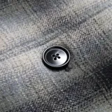 Campera a cuadros gris y negro con cuello de pana negro, cierre con botones y bolsillos frontales con solapa.