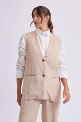 Chaleco largo color beige con solapas, cierre con dos botones y bolsillos delanteros.