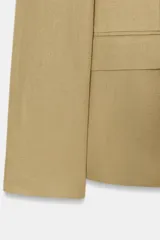 Blazer color beige de cuello solapa y manga larga. Tiene bolsillos con solapa en el delantero y cierre frontal con un botón.