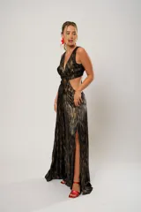 Vestido largo de fiesta con estampado abstracto en tonos dorados y negros. Tiene escote en V, corte en la cintura y aberturas laterales.