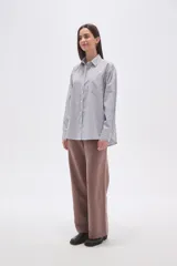 Camisa de algodón holgada con cuello camisa, botones frontales y estampado de rayas verticales finas en blanco, negro y rosado.