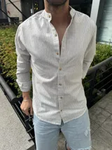 Camisa de manga larga con cuello mao y cierre frontal con botones de madera. Diseño a rayas verticales en tonos beige y gris.