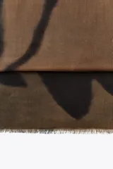 Pañuelo rectangular de modal con estampado de hojas en tonos marrón y negro, y terminaciones deshilachadas.