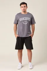 Bermuda deportiva gris de nylon, de corte suelto, con cintura elástica y cordón de ajuste. Cuenta con detalles de líneas negras en los costados y bolsillos laterales con cierre.