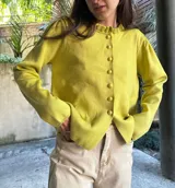 Saco de punto color amarillo, con cuello redondo con volados y cierre frontal con botones.