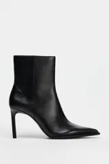 Botín negro de cuero con tacón fino, punta fina y cierre lateral con cremallera.