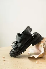 Sandalias negras de cuero con plataforma y hebillas metálicas.