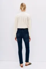 Pantalón de jean azul oscuro, corte slim, tiro alto y bolsillos delanteros y traseros.