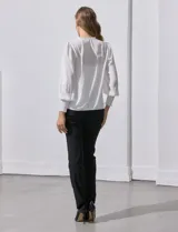 Blusa blanca de gasa marca Tahari, con escote en V, apliques de botones y detalle de punto smock en hombros y puños. Incluye musculosa a tono.