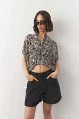 Blusa de manga corta con estampado de hojas en tonos negro y blanco, con cuello mao y botones a tono.
