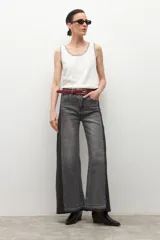 Pantalón de jean wide leg de tiro alto, bicolor, con paneles en gris lavado claro y gris oscuro/negro. Presenta costuras visibles y dobladillo deshilachado en los bajos.