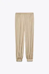 Pantalón bombacho color beige de tiro alto, con elástico en la cintura y en los tobillos.