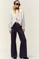 Camisa blanca de cuello redondo con detalle de nido de abeja y entredoses. Manga larga con bordados a tono y cierre trasero con botones.