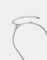 Collar corto plateado con dije de moño con strass y cierre de mosquetón.