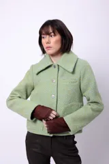 Campera corta de poliéster texturizado color verde oscuro, con cuello camisero, cierre frontal con botones a presión, bolsillos delanteros y forro interior. Incluye pins decorativos.