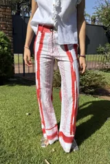 Pantalón de corte recto con estampado de rayas verticales rojas y texto en color negro.